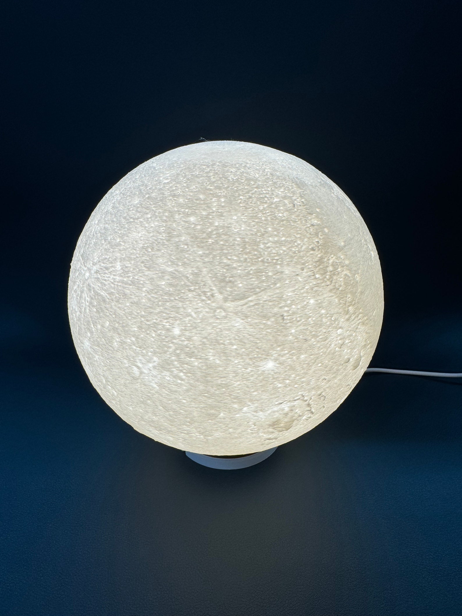 Close-up of a 3D printed moon lamp showing the moon texture and LED table lamp finish